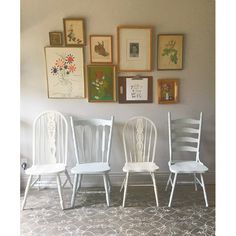 four white chairs are lined up against a wall with pictures on the wall behind them