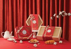 three red boxes sitting on top of a table next to a teapot and cup