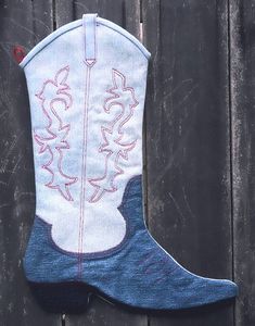 a pair of cowboy boots sitting on top of a wooden fence covered in blue and white fabric