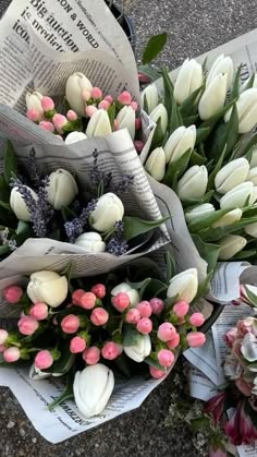 two bouquets of tulips and other flowers sit on the ground next to newspapers