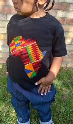 This African print kid's tee, featuring cultural appliquéd designs, is an ideal birthday gift for kids. Let your little one celebrate their cultural heritage in style with this unique and personalized black t-shirt. DETAILS: - Made from 100% cotton - Crew neck style T-shirt with short sleeves - Fabric pattern placement may vary. - Fabrics are chosen at random, so each T-shirt is unique!  CARE INSTRUCTIONS: - Recommended wash at 30º degrees. Africa Day, Map Of Africa, Kids Tshirt, Shirt Design Ideas, T Shirt Design Ideas, Birthday Gifts For Kids, Style T Shirt, Fabric Pattern, Kid Tees