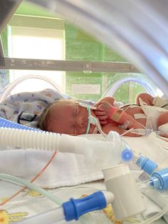 a baby laying in a hospital bed next to an oxygen tube and bottle filled with water