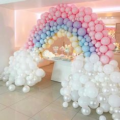 there is a large arch made out of balloons in the shape of a rainbow on display