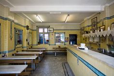 an empty restaurant with tables and benches in the front row, along with pictures on the wall