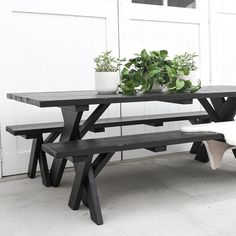 a table with two benches and a potted plant sitting on top of it next to a white door