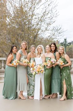 a group of women standing next to each other wearing dresses and holding bouquets in their hands