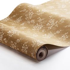 a roll of brown and white wallpaper with flowers on it's side, laying on top of a table