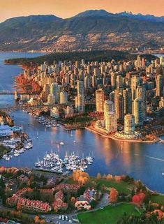 an aerial view of a city with boats in the water and mountains in the background