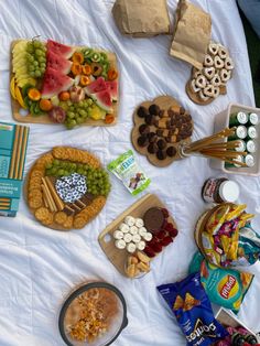 an assortment of snacks are laid out on a bed with white sheets and paper bags