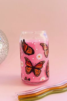 a pink candle with butterflies painted on it