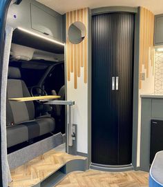 the interior of an rv with wood flooring and grey walls, including a black door