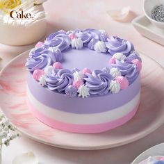 there is a cake on the table with purple frosting and white flowers around it