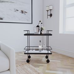 a living room with a white couch and two black trays on wheels in front of a window