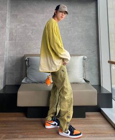 a young man standing on top of a wooden floor next to a bed and pillows