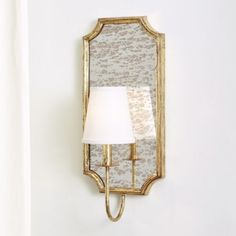 a wall mounted mirror on the side of a white wall next to a light fixture