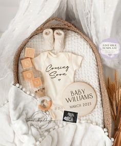 a baby announcement is displayed on a white blanket with some items in the basket next to it