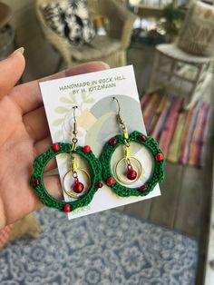 a pair of green and red beaded hoop earrings with beads on each earring