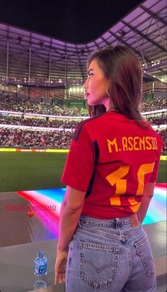 a woman standing on top of a baseball field next to a stadium filled with people