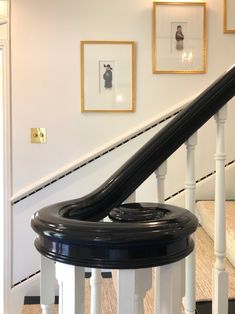 a black and white banister with pictures on the wall behind it in a house