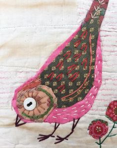 a pink bird sitting on top of a white wall next to red and green flowers