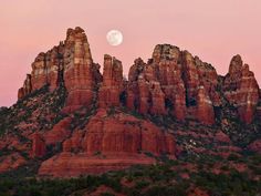 the full moon is setting over red rock formations