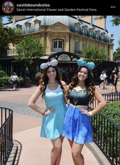 two young women standing next to each other in front of a building with disney ears on