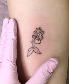 a little mermaid tattoo on the side of a woman's thigh, with her arm behind her back