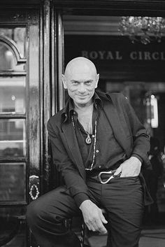 an old man sitting on a chair in front of a doorway with the words royal circle written