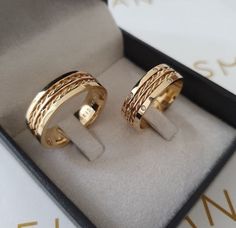 two gold rings sitting in a box on top of a table