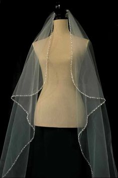 a white veil with beaded trims on top of a mannequin torso