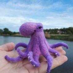 a purple stuffed animal is held in someone's hand