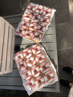 two boxes filled with baseball cookies on top of a table