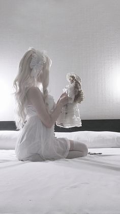 a woman sitting on top of a bed holding a teddy bear