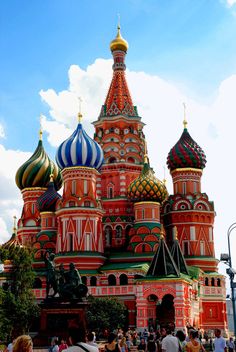 many people are walking around in front of an ornate building with domes on the top