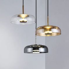 three lights hanging from the ceiling in a room with white walls and grey flooring