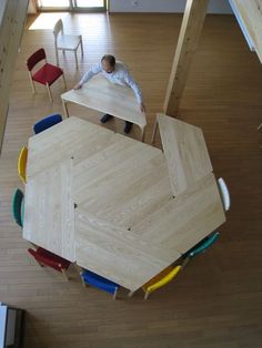 an overhead view of a table with chairs and a man standing in the back ground