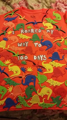 an orange shirt with dinosaurs on it that says i roar my way to 100 days