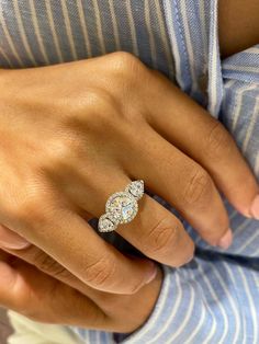 a woman's hand with a diamond ring on her left hand and a striped shirt on the right