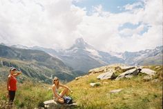 two people sitting on rocks in the mountains