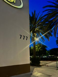 a large sign on the side of a building with palm trees in front of it