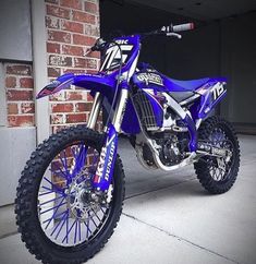 a blue dirt bike parked next to a brick wall