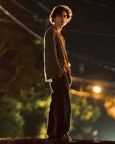 a young man standing on top of a roof next to a street light at night