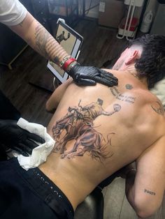 a man with tattoos on his back is being examined by a tattooist at the same time