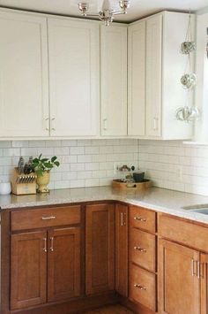 a kitchen with wooden cabinets and white tile backsplash, wood flooring and light fixtures