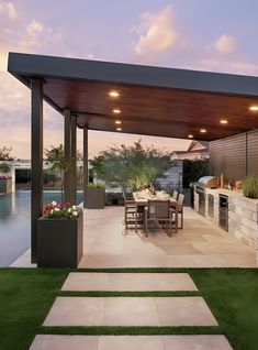 an outdoor kitchen and dining area with grass