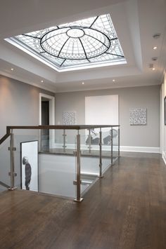 an empty room with glass railings and skylight in the ceiling, along with hardwood flooring