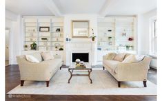 a living room with two couches and a coffee table in front of a fireplace