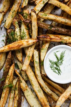 baked french fries with dill sprig and ranch dip on top, ready to be served