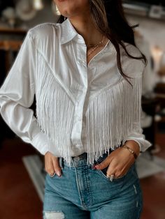 Elevate your wardrobe with our Satin Button Up Blouse featuring a showstopping Chevron Fringe design on the front and back. The Perfect Boho Western Moment for adding texture and style to any outfit. Color: Pure White Front & Back Fringe Relaxed Fit Button Up Feature Length 27" Cristina is wearing a size Small 100% Polyester Brand: BlueB Cowgirl Fringe Outfits, Western Button Up Shirts Woman, White Western Outfit, French Cowgirl, Fringe Clothing, Fringe Blouse, Western Blouse, Classy Cowgirl, Fringe Shirt