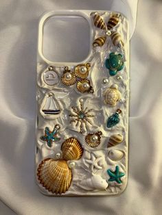 a cell phone case with shells and seashells on the back, sitting on a white sheet